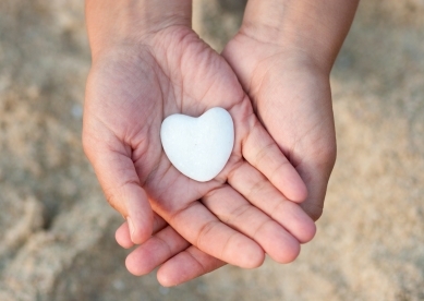 Hands holding stone that is shaped like a heart