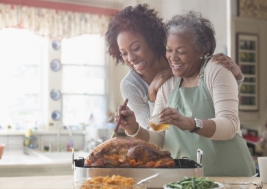 mother and daughter smiling in kitchen with turkey