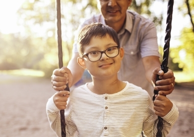 Boy being pushed on swing by father